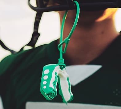 Green mouthguard hanging from football helmet