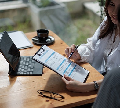 Two people sitting at desk, discussing paperwork