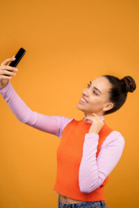 Woman taking a selfie against orange background