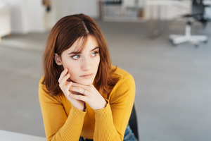 Woman in yellow shirt sitting and looking concerned